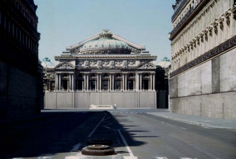 An image of a Parisan street with grand buildings with facades which are boarded up at street level