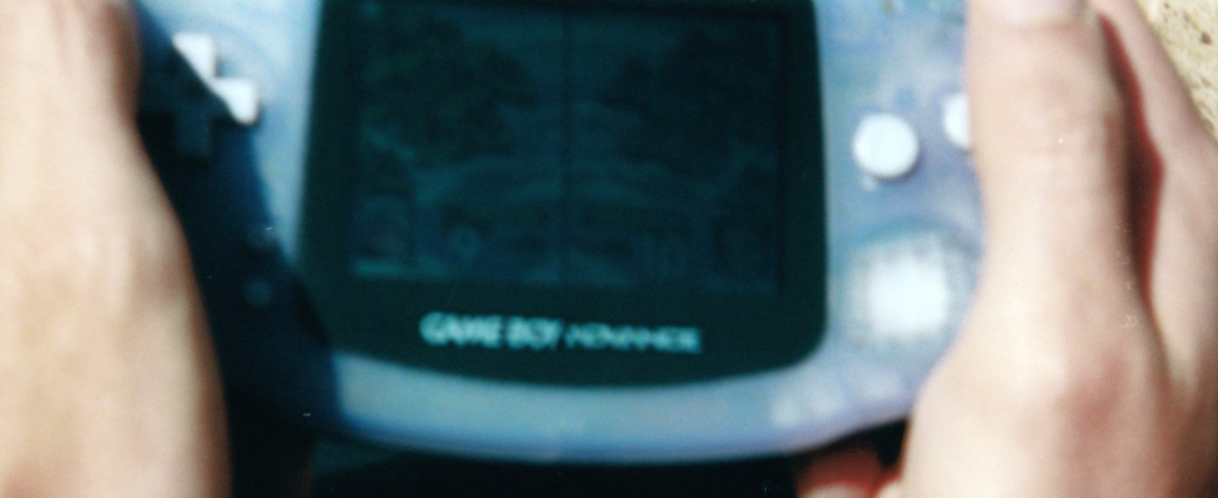 A blurry picture of a Nintendo GBA with Advance Wars barely visible playing on its screen