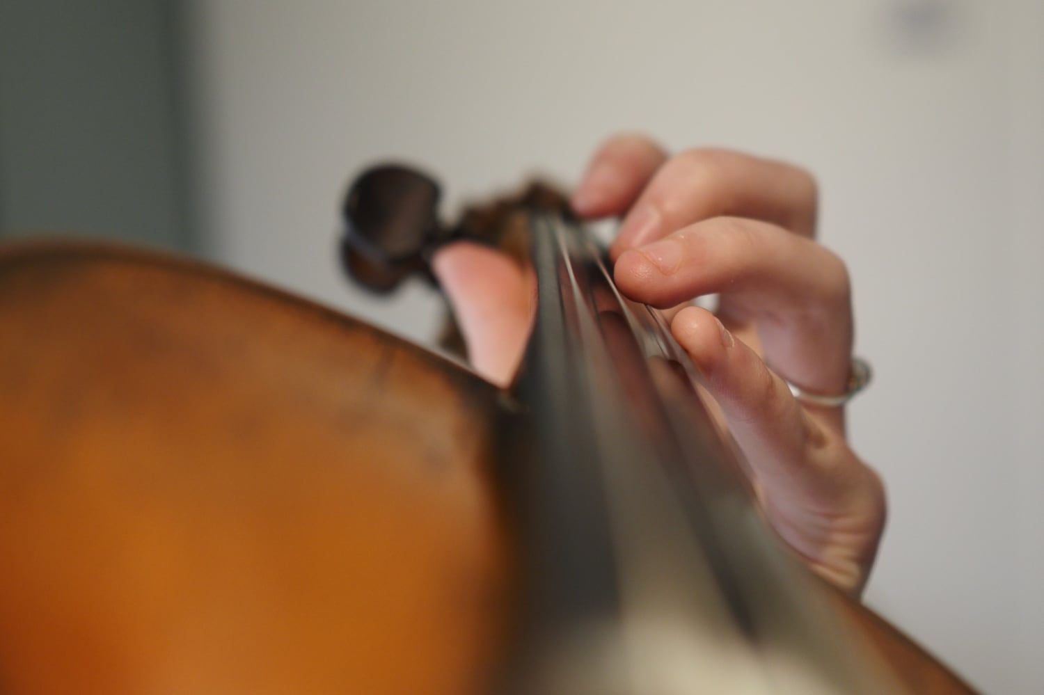 A view down the body of a violin towards the violinist’s fingers holding the neck.